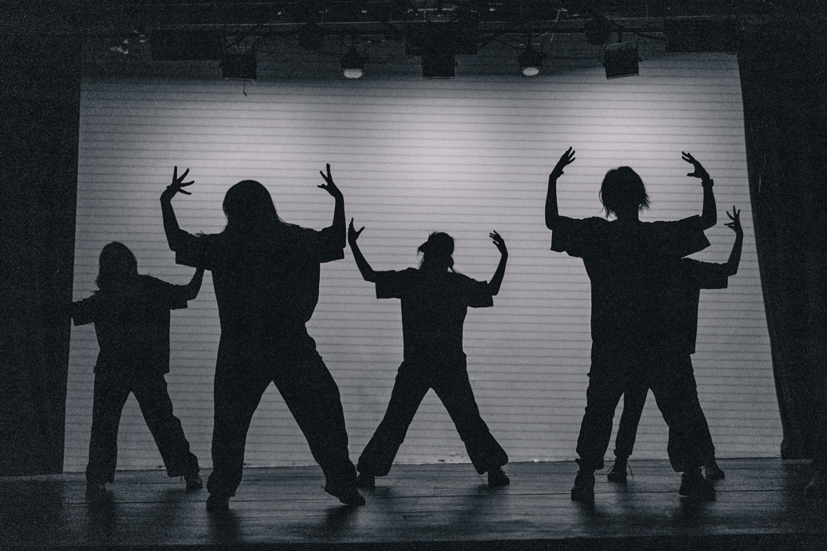 Dancers silhouetted against a bright backdrop mid-pose during a stage performance