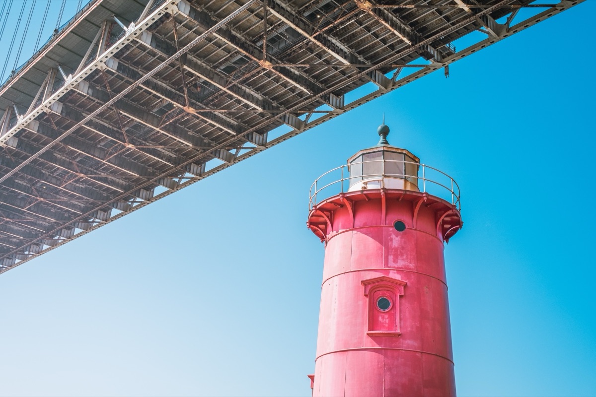 The Little Red Lighthouse beneath the George Washington Bridge against a clear blue sky, New York