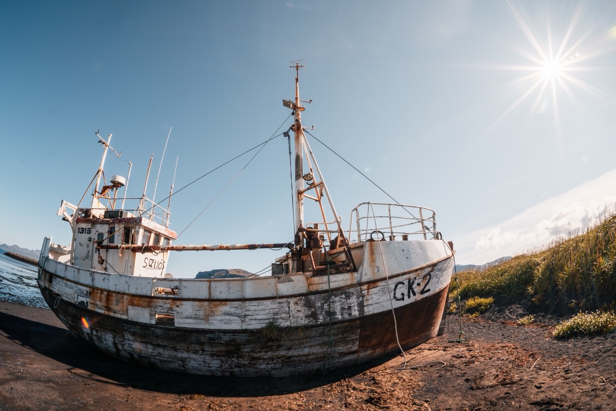 The wreck of the fishing boat GK-2 beached on the shore under a bright sunburst, Iceland