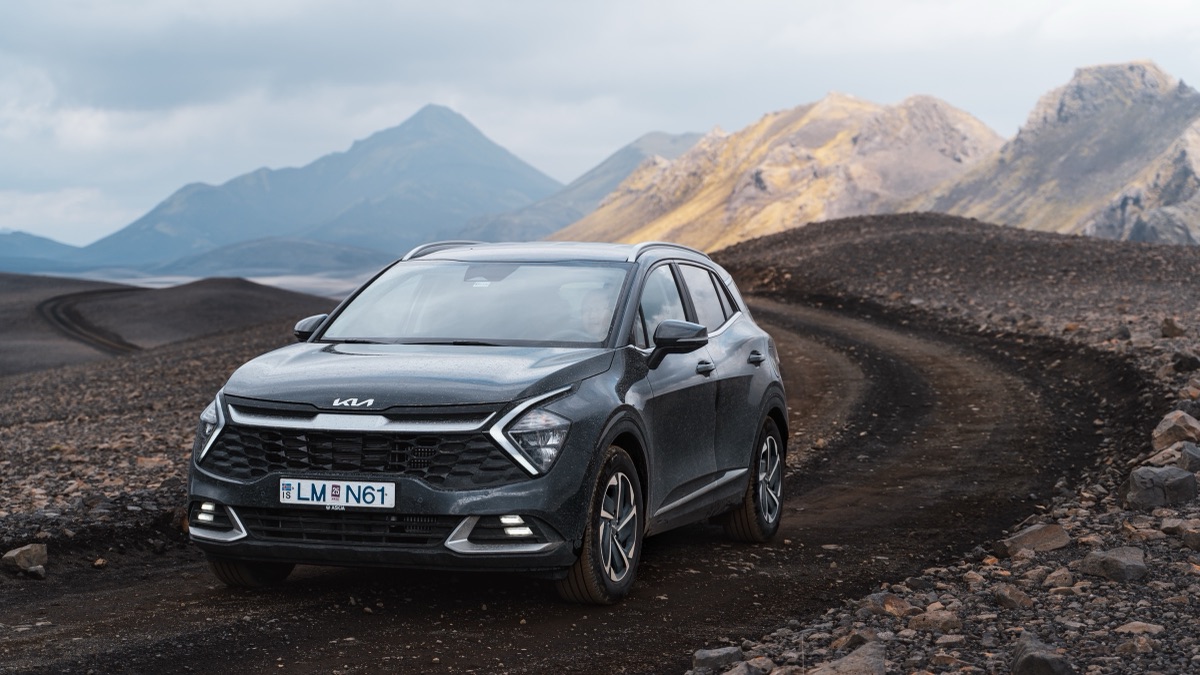 A rental SUV parked on a gravel track below rhyolite peaks in the Icelandic highlands
