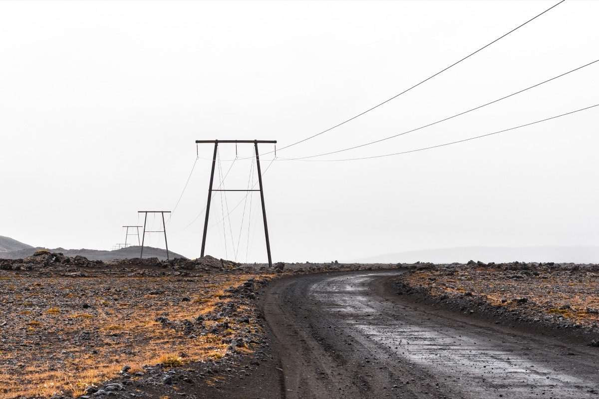 Power lines following a gravel road across the barren Icelandic interior