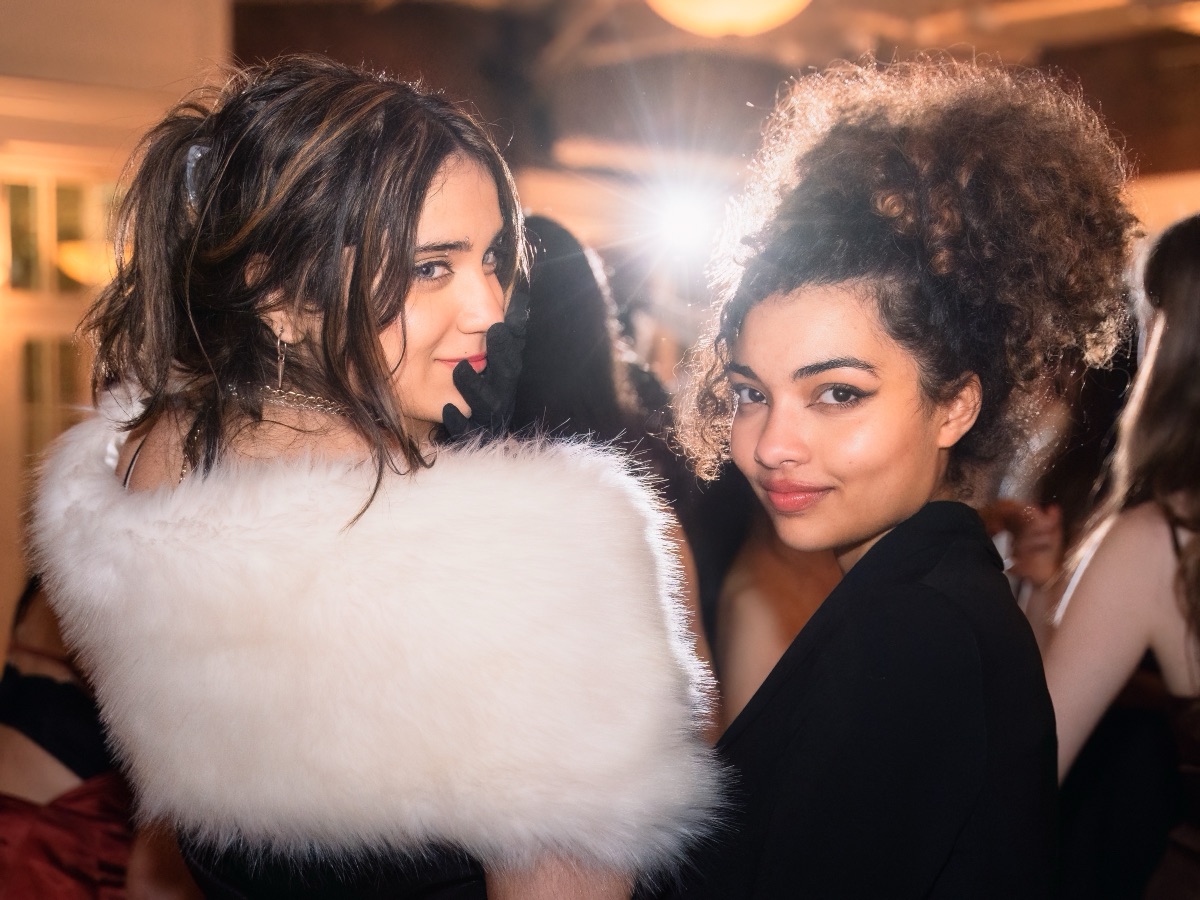 Two friends glancing back over their shoulders at a formal dance