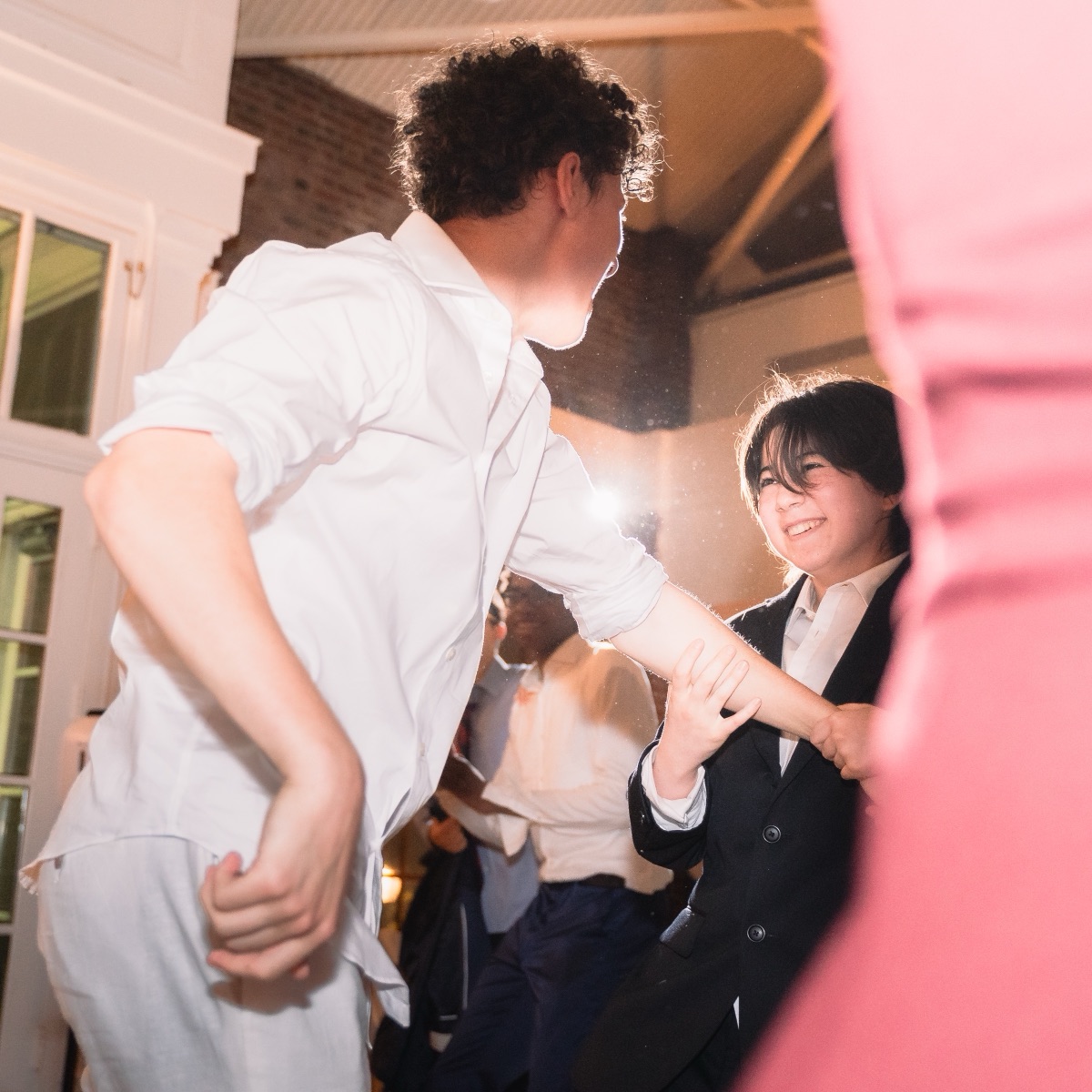 Two students dancing and laughing under the flash at a school formal